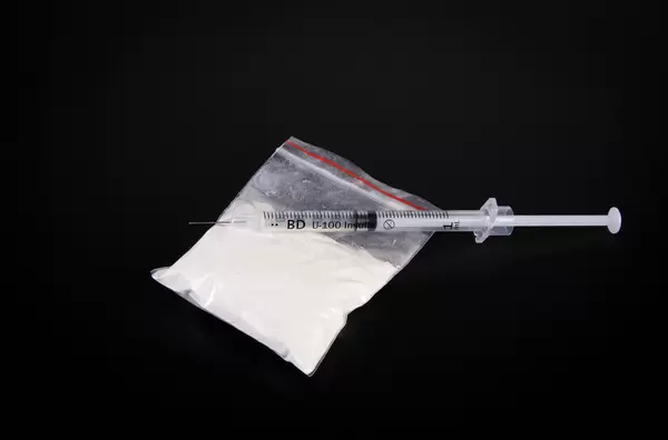 Cocaine and syringe on dark background