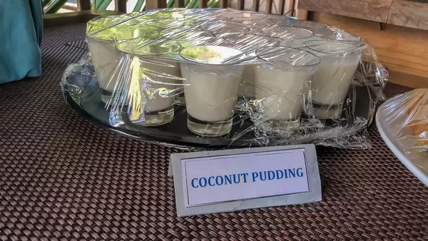 Coconut pudding in glasses on black plate covered with plastic wrap at Constance Ophelia Resort in the Seychelles