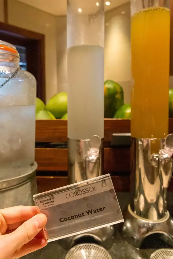 Coconut Water sign in front of juice dispenser of Constance Ephelia Resort in Mahé, Seychelles