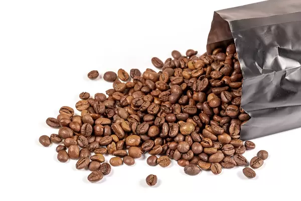 Coffee beans scattered from the packaging on white