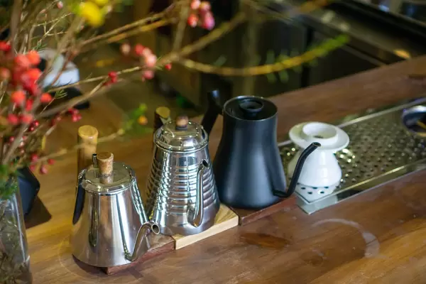 Coffee Pour Over Gooseneck Kettles in different Designs on a Wooden Countertop of a Bar Style Cafe