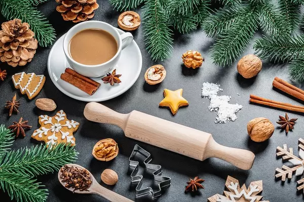 Coffee with anise and cinnamon on a New Year's background with a rolling pin, Christmas tree branches, gingerbread and cones