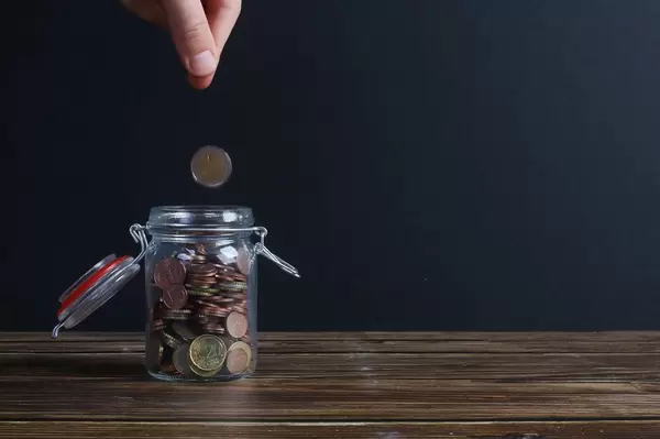 Coin falling into money jar