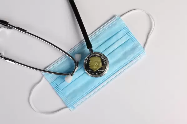 Coin with Donald Trump and stethoscope on face mask