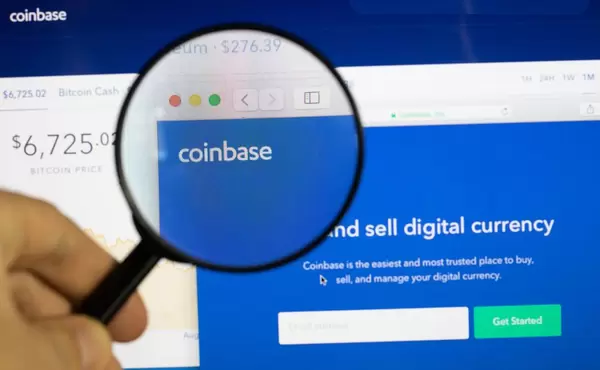 Coinbase-Logo am PC-Monitor, durch eine Lupe fotografiert