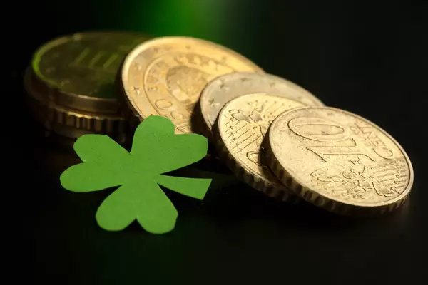 Coins and shamrock leaf on dark background, close up