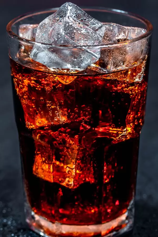 Cola mit Eiswürfeln in einem Glas auf schwarzem Hintergrund