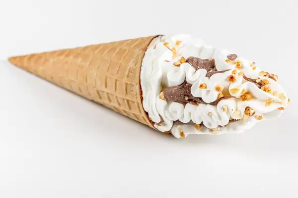 Cold ice cream with chocolate and nuts in a waffle cone on a white background