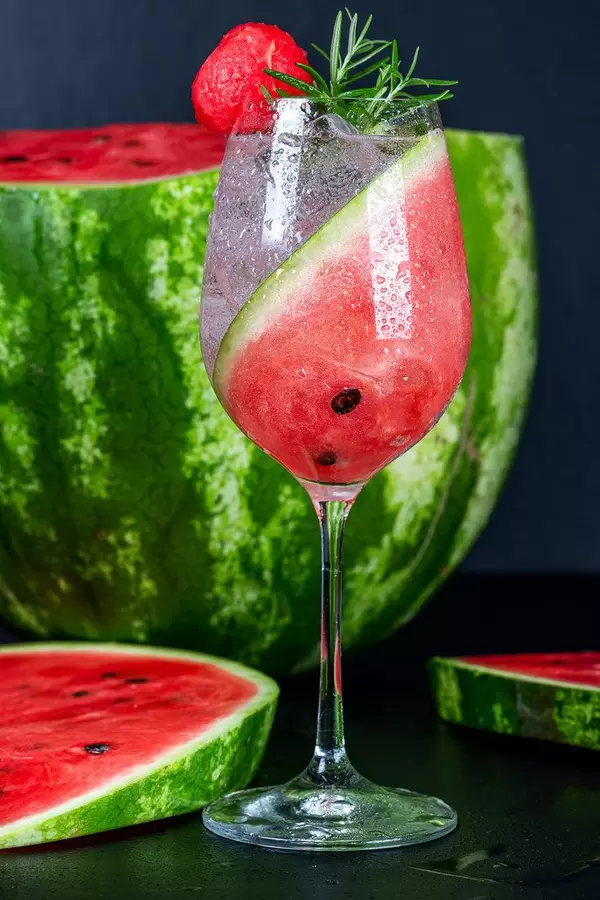 Cold summer cocktail with fresh watermelon and rosemary on a black background