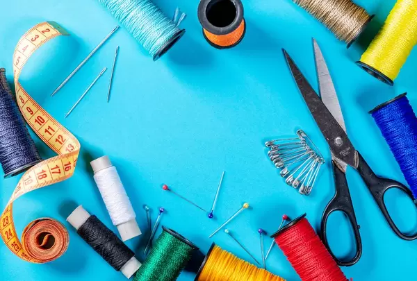 Collection of attributes for embroidery and sewing on blue background