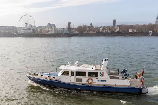 Cologne, Germany: police motorboat patrolling the Rhine with ferris wheel in the background
