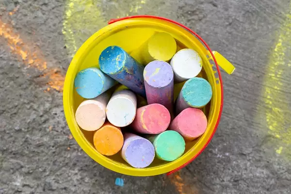 Colored chalk in a yellow bucket. Top view