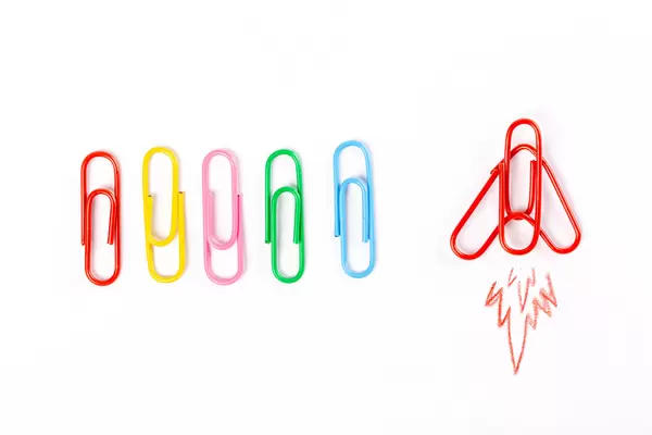 Colored paper clips on white background and airplane take off, forward movement concept