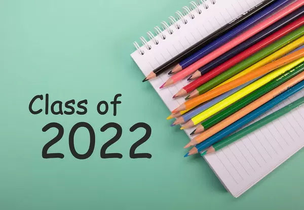 Colored pencils and notebook with Class of 2022 text on green background