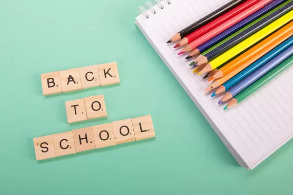 Colored pencils and wooden blocks with Back to School text on green background