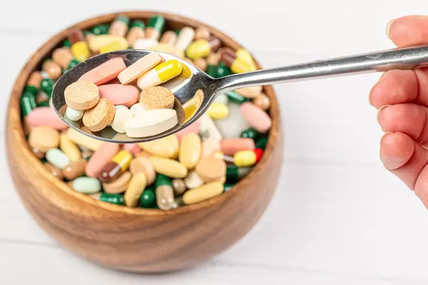 Colorful capsules and tablets in a spoon, close-up