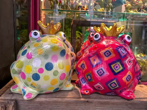 Colorful frog kings made of porcelain, on wooden table