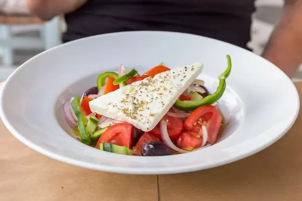 Colorful Greek salad wit feta cheese and fresh vegetables on a white plate