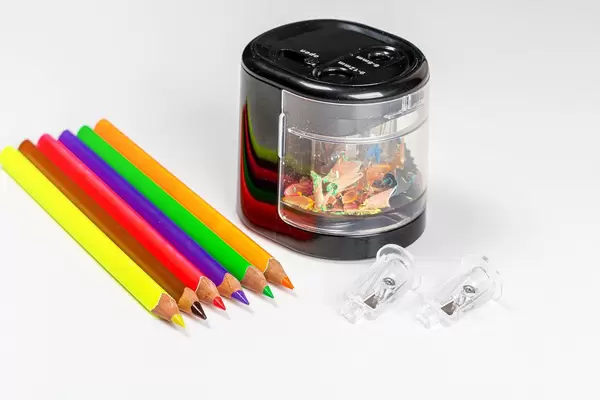 Colorful pencils and electric pencil sharpener on white background