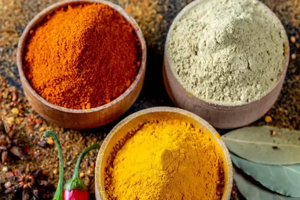 Colorful spices in wooden bowls on a dark background