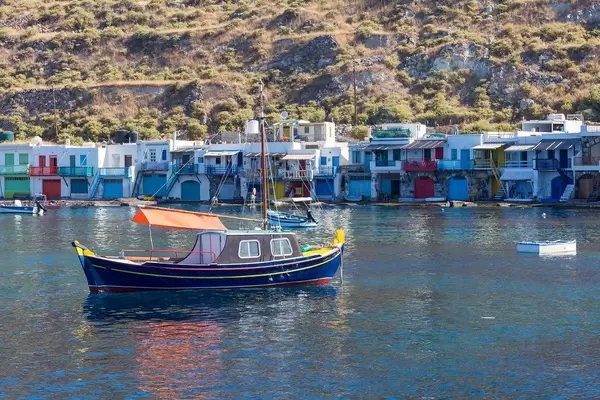 Colours of Greece: blue, yellow and red fishing boat in front of the fisherman's village of Klima on Milos