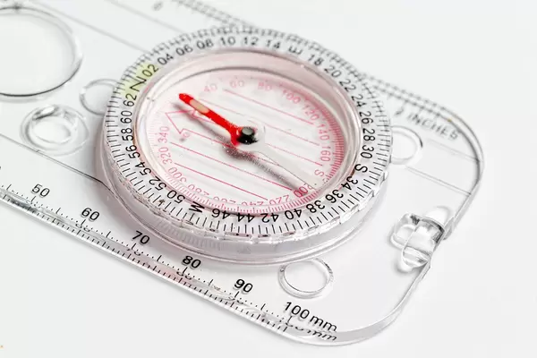 Compact compass with ruler on white background close-up