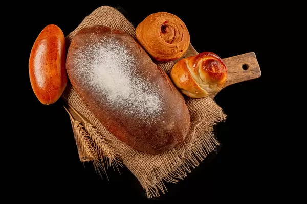Composition with bread and buns on black, top view