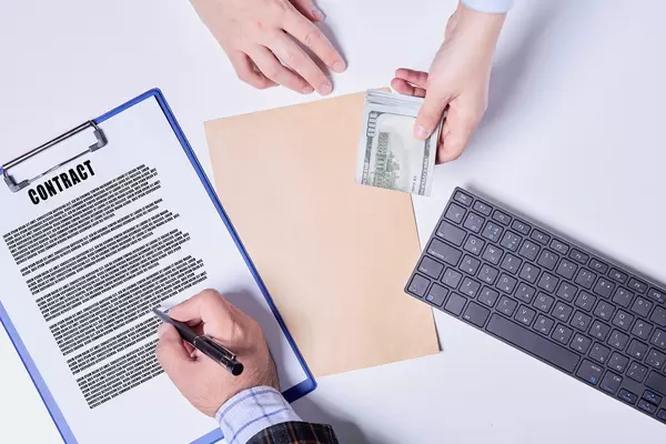 Concept - corruption. Giving a bribe. Money in hand. Sign the document