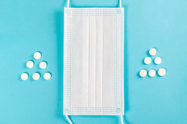 Concept of Christmas and protection of your health - mask and Christmas trees from pills on blue