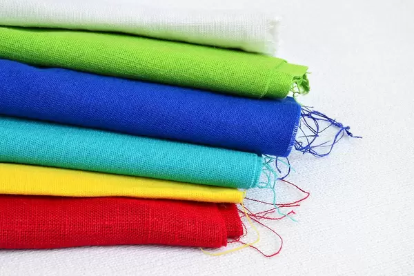 Concept of DIY clothes: stack of fabrics for sewing