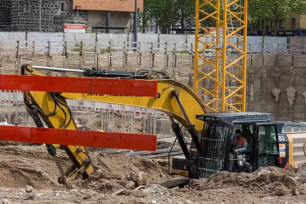 Construction worker sits in a crawler excavator at the construction site at Rudolfplatz in Cologne