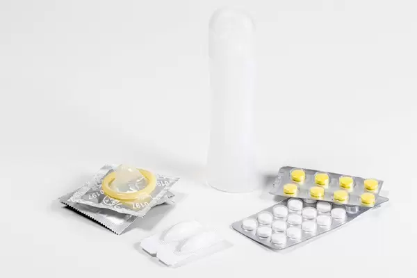 Contraceptive pills, suppositories and condoms on white background. Concept of birth control