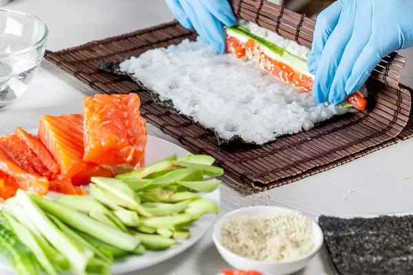 Cook preparing sushi with salmon and avocado (Flip 2019)