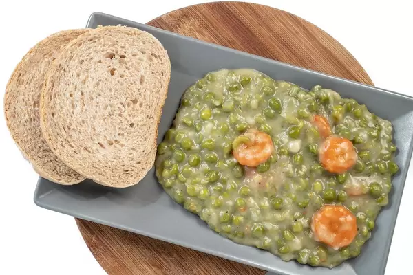 Cooked Green Peas with Carrots served on the plate with bread (Flip 2019)
