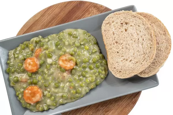 Cooked Green Peas with Carrots served on the plate with bread