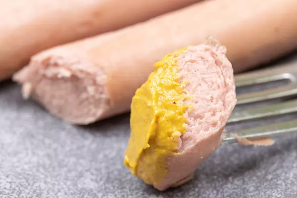 Cooked Hot Dog slice with Mustard on the fork