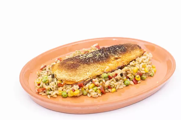 Cooked Rice with Vegetables and fryed Hake served on the plate
