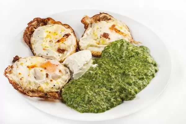 Cooked Spinach and Fried Eggs in the white plate