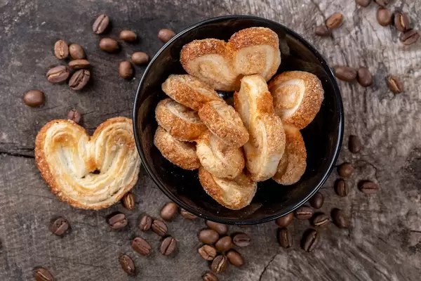 Cookies in a black bowl on a wooden background with coffee beans