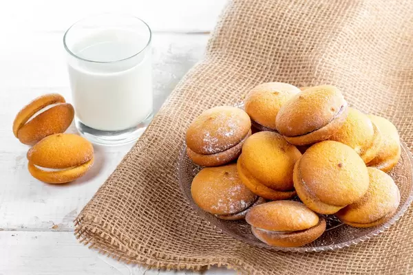 Cookies with cream and coconut on a wooden table with a glass of milk (Flip 2019)