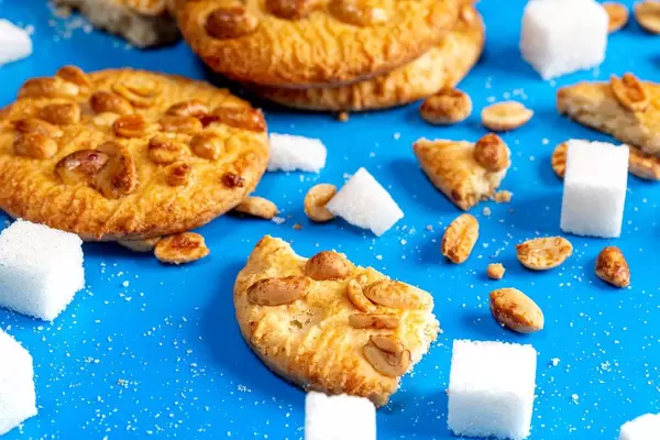 Cookies with peanuts and sugar cubes on a blue background closeup