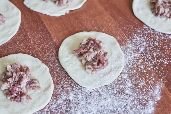 Cooking homemade dumplings with meat on wooden table