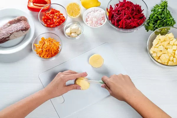 Cooking process on the kitchen table with ingredients for borscht (beet soup with meat)