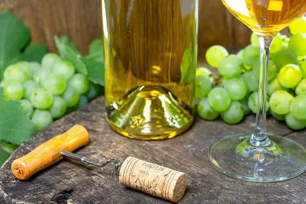 Corkscrew with a crust on the background of a bottle of white wine and grapes (Flip 2019)