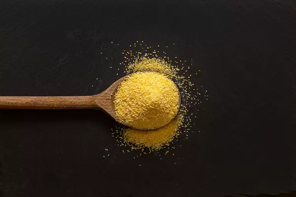 Corn Flour on the wooden spoon with dark background and copy space