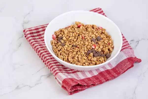 Cornflakes mit Schokostückchen und Erdbeeren, auf einem roten Geschirrtuch