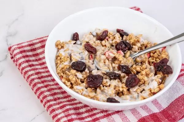 Cornflakes-Schüssel mit Joghurt, Schokostreusel, Erdbeeren und getrockneten Preiselbeeren
