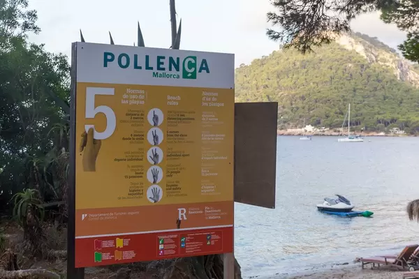 Corona-Abstandregeln am Strand auf Spanisch, Englisch und Katalanisch in Pollença auf Mallorca