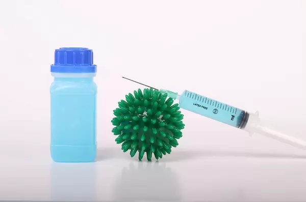 Coronavirus bacteria with syringe and bottle with blue fluid
