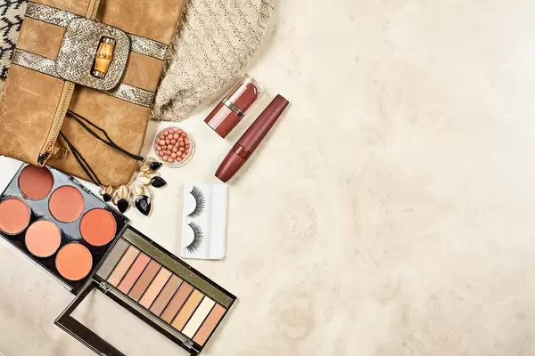 Cosmetic bag with make-up products on marble background